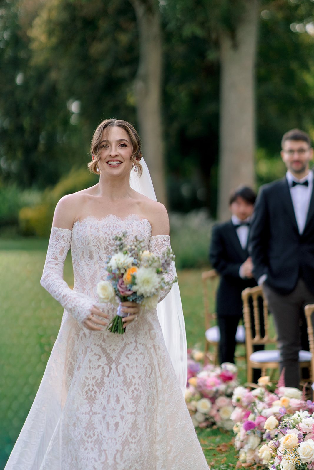 Mariée souriante tenant un bouquet champêtre dans le parc d'un château