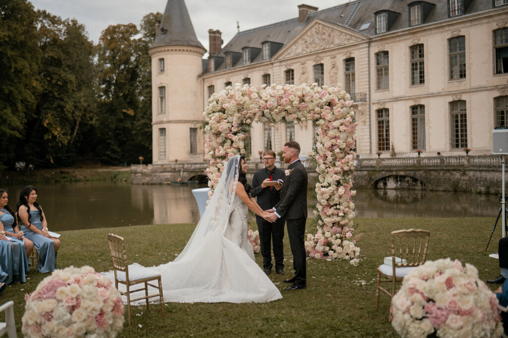 Arche florale blanche et rose pour une cérémonie de mariage devant un château – réalisation Hibiscus Events