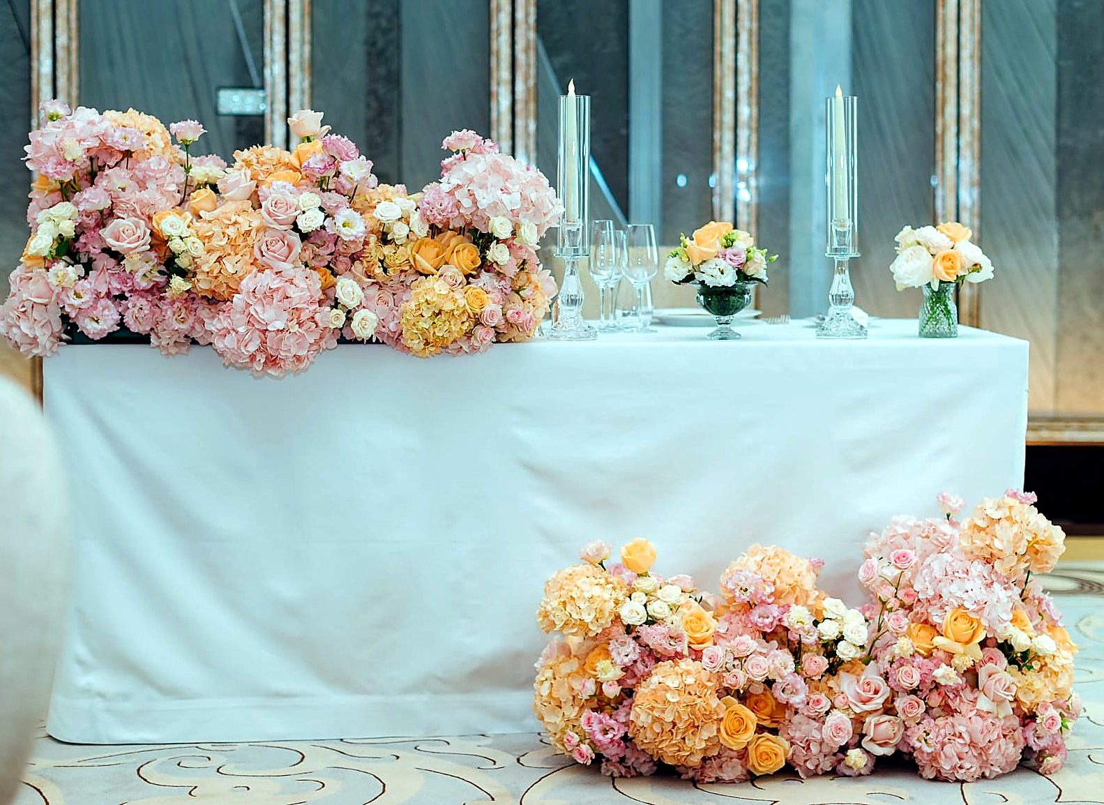 Détail sweet heart table florale aux tons pêche, rose et blanc avec bougies