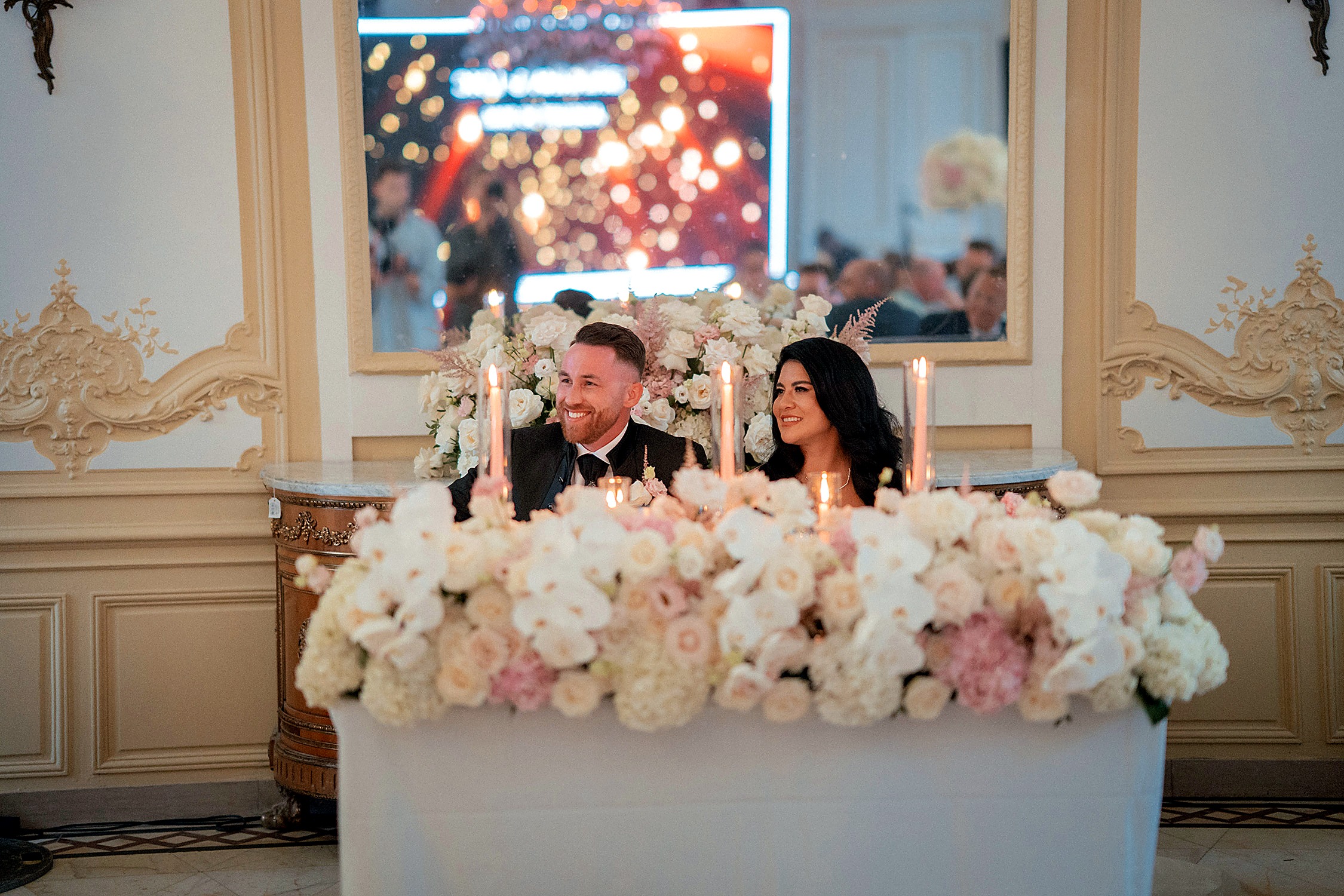Mariés installés à leur sweet heart table florale blanche et rose